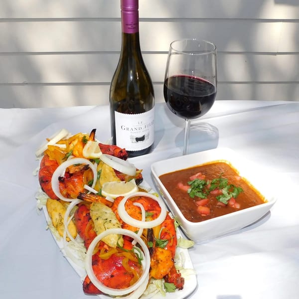 Indian tandoori shrimp and chicken, with a side of curry, wine, and a glass of red wine.